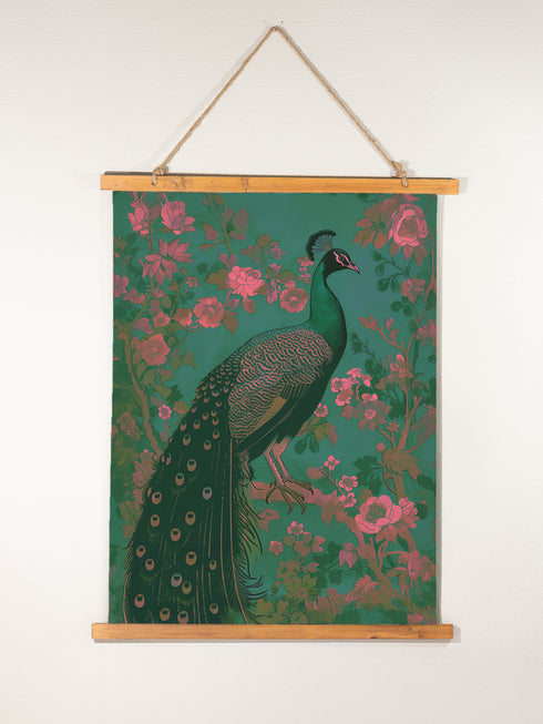A wall tapestry featuring a detailed teal peacock with golden accents and intricate plumage, surrounded by ornate golden flowers and foliage on an emerald green background, mounted between wooden dowels with twine.